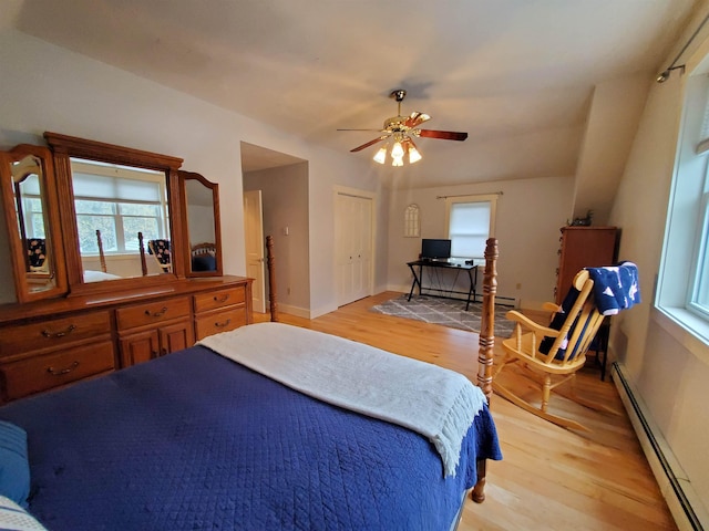 bedroom featuring a baseboard radiator, light wood-style flooring, ceiling fan, and baseboards
