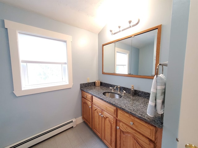 bathroom with a baseboard heating unit, healthy amount of natural light, vanity, vaulted ceiling, and baseboards