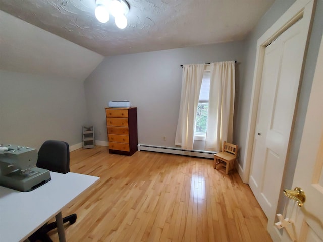 office space with a baseboard heating unit, light wood-style flooring, lofted ceiling, and baseboards
