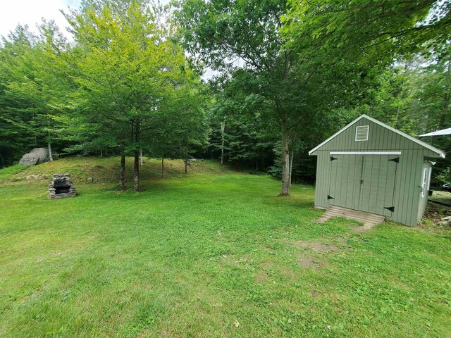 view of green lawn with a storage unit and an outdoor structure