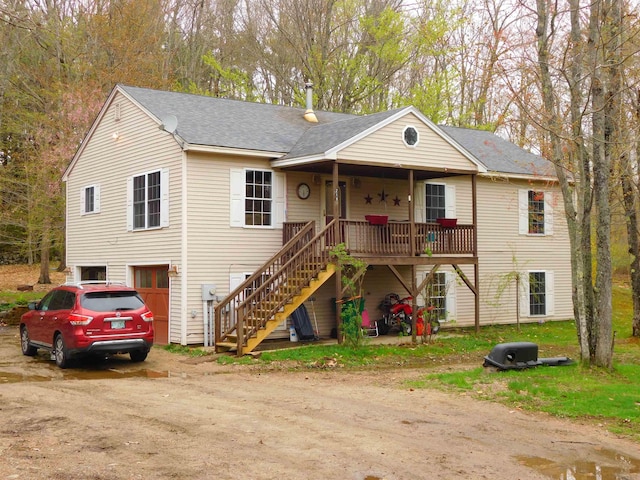 view of front of home featuring driveway, a garage, roof with shingles, and stairs