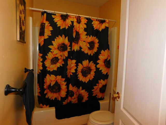 bathroom featuring toilet and shower / tub combo with curtain