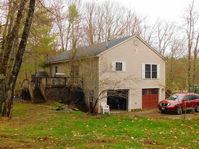 back of house featuring stairs, an attached garage, a wooden deck, and a yard