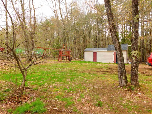 view of green lawn with a storage unit and an outdoor structure