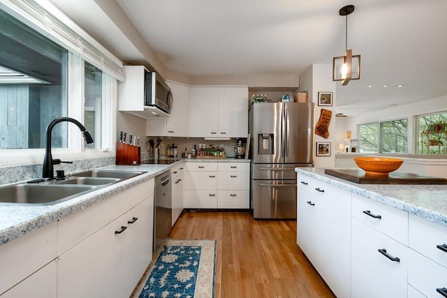 113 Watchtower Rd, Hopkinton, NH 03229 - kitchen with stainless steel appliances, a sink, light wood-style floors, white cabinetry, and decorative light fixtures