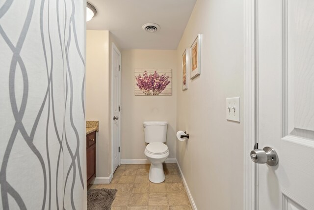 bathroom featuring toilet, vanity, and baseboards