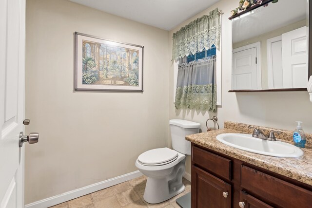 bathroom with toilet, baseboards, and vanity