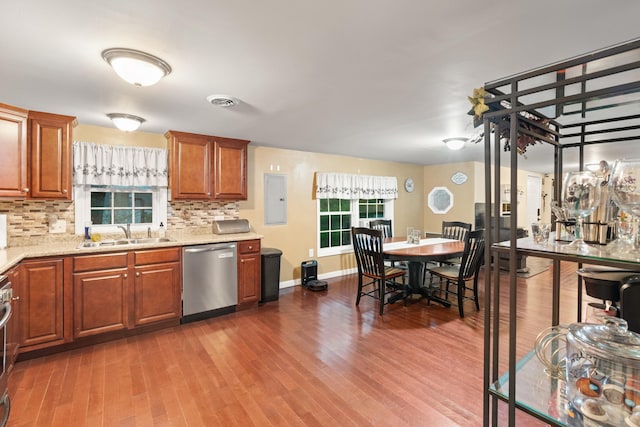 kitchen featuring dishwasher, a sink, tasteful backsplash, wood finished floors, and brown cabinets