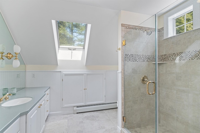 full bathroom featuring baseboard heating, a stall shower, a skylight, vanity, and a wainscoted wall