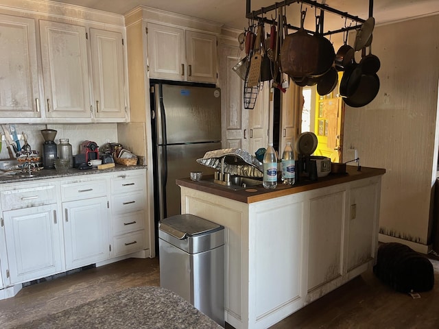 kitchen with freestanding refrigerator, dark countertops, white cabinets, and a sink