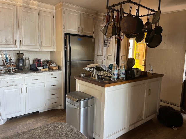 kitchen featuring freestanding refrigerator, a sink, white cabinetry, and tasteful backsplash