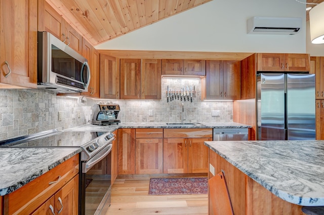 kitchen featuring appliances with stainless steel finishes, a sink, an AC wall unit, light wood-style floors, and backsplash