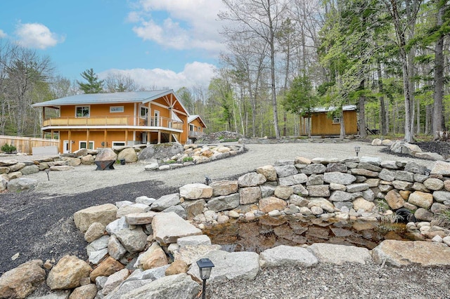 rear view of house featuring a deck, an outdoor structure, and metal roof