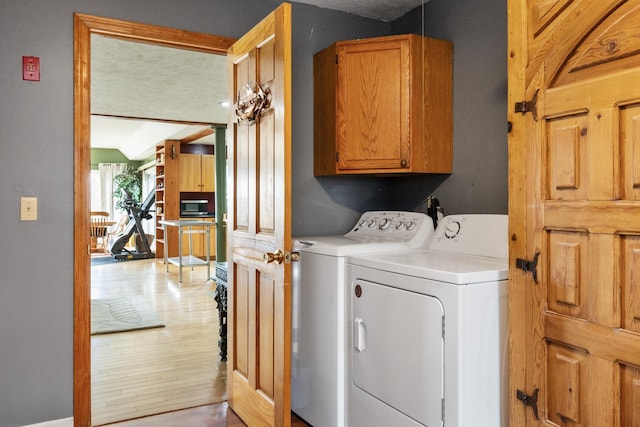 331 Gilman Rd, Sheldon, VT 05450 - clothes washing area with cabinet space, washing machine and clothes dryer, and light wood-style flooring
