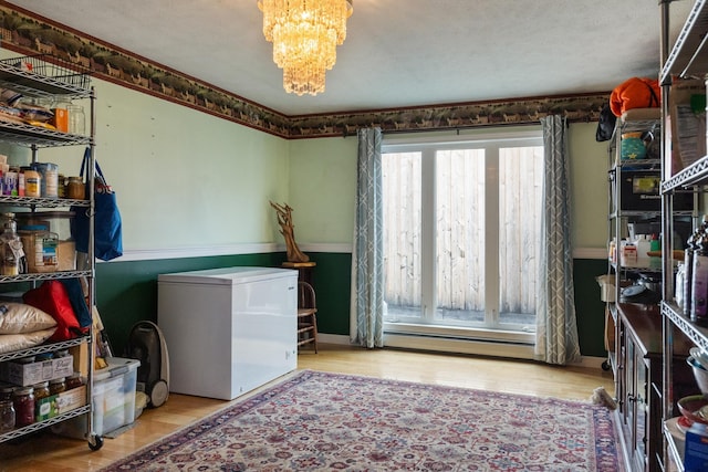 331 Gilman Rd, Sheldon, VT 05450 - laundry room featuring a baseboard heating unit, a chandelier, and wood finished floors