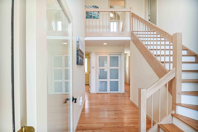 stairs with wood finished floors, a high ceiling, french doors, and baseboards