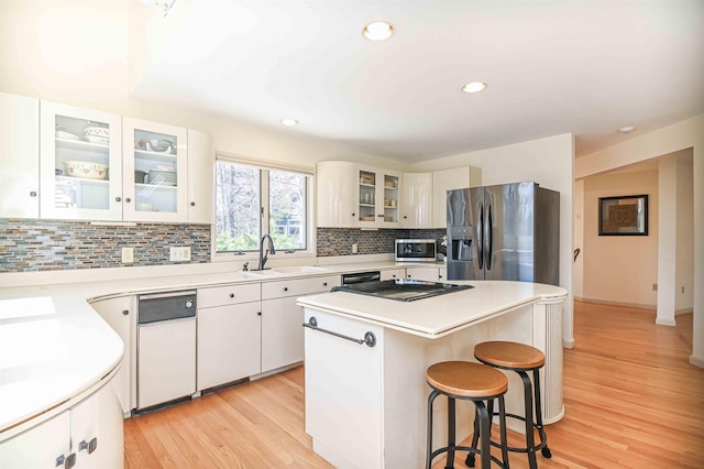 kitchen with a sink, appliances with stainless steel finishes, a kitchen breakfast bar, a kitchen island, and backsplash