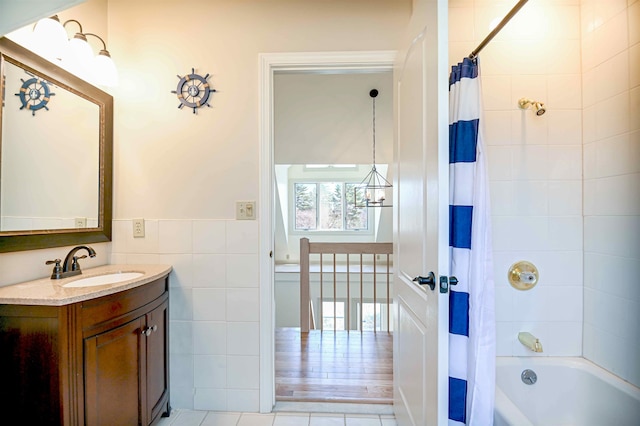 full bath with vanity, shower / bath combo, tile walls, tile patterned floors, and a wainscoted wall