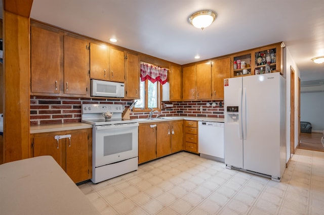 kitchen featuring white appliances, light flooring, a sink, brown cabinets, and light countertops