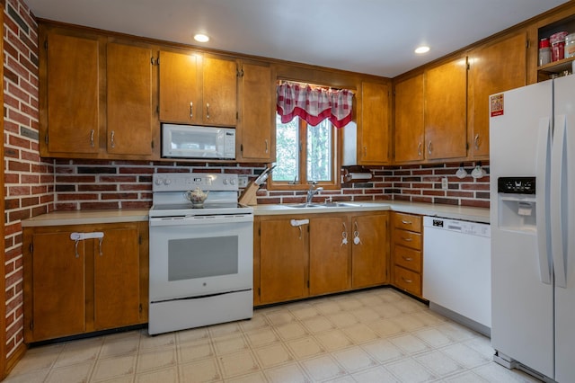 kitchen featuring white appliances, a sink, light flooring, and brown cabinets