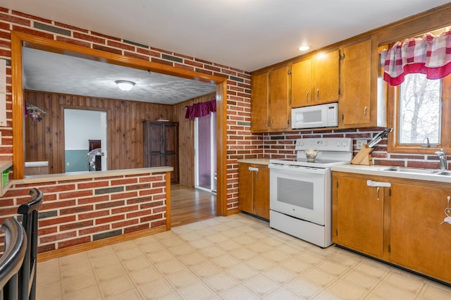 kitchen with white appliances, light floors, a sink, light countertops, and brown cabinets