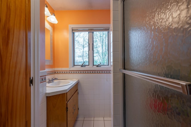 bathroom with tile walls, wainscoting, tile patterned flooring, and vanity