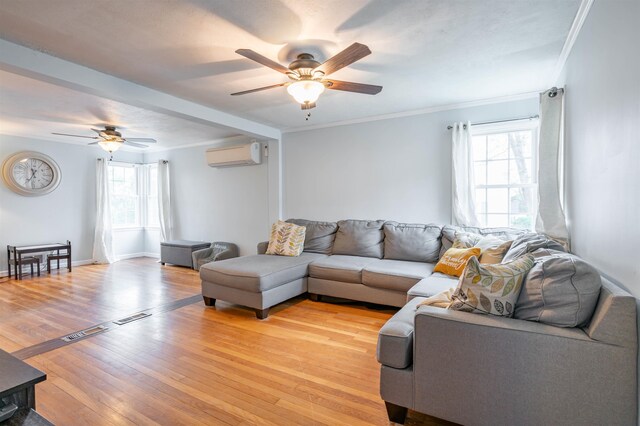 living area featuring ceiling fan, a wall mounted air conditioner, light wood-style flooring, crown molding, and baseboards