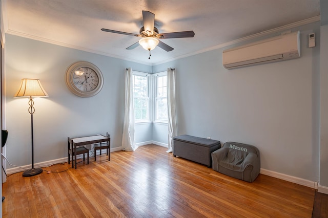 sitting room with a wall unit AC, hardwood / wood-style flooring, a ceiling fan, crown molding, and baseboards