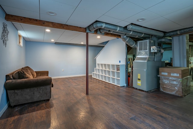 finished basement with wood finished floors, baseboards, heating unit, and recessed lighting