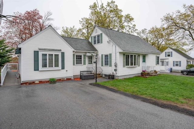 view of front of property with a shingled roof, a front lawn, and central air condition unit