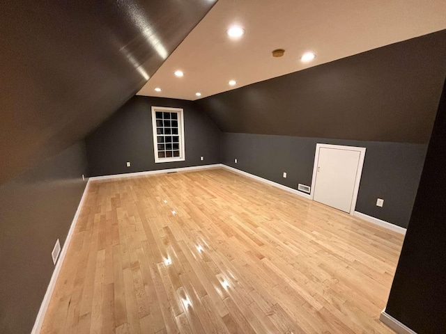 additional living space featuring baseboards, light wood-type flooring, vaulted ceiling, and recessed lighting