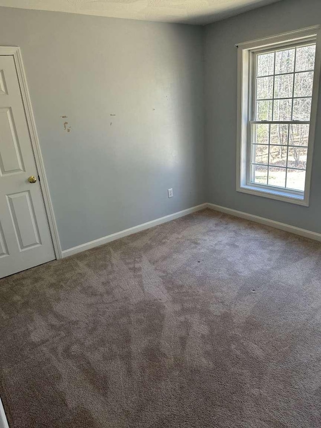 unfurnished room featuring carpet floors and baseboards