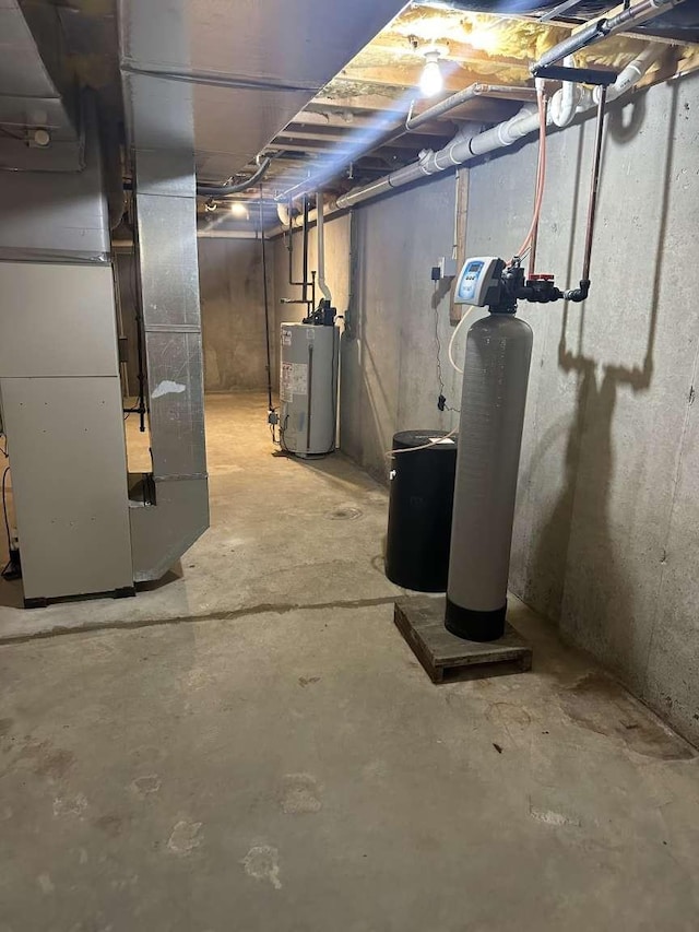 unfinished below grade area featuring water heater, heating unit, and a water softener