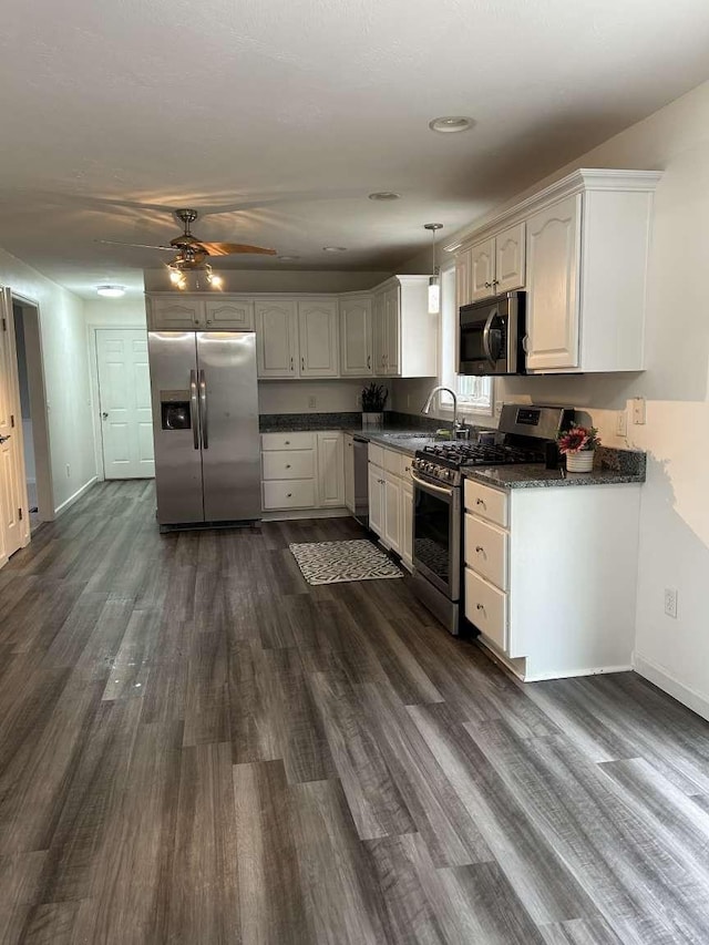 kitchen with stainless steel appliances, dark countertops, dark wood-style flooring, a ceiling fan, and white cabinets