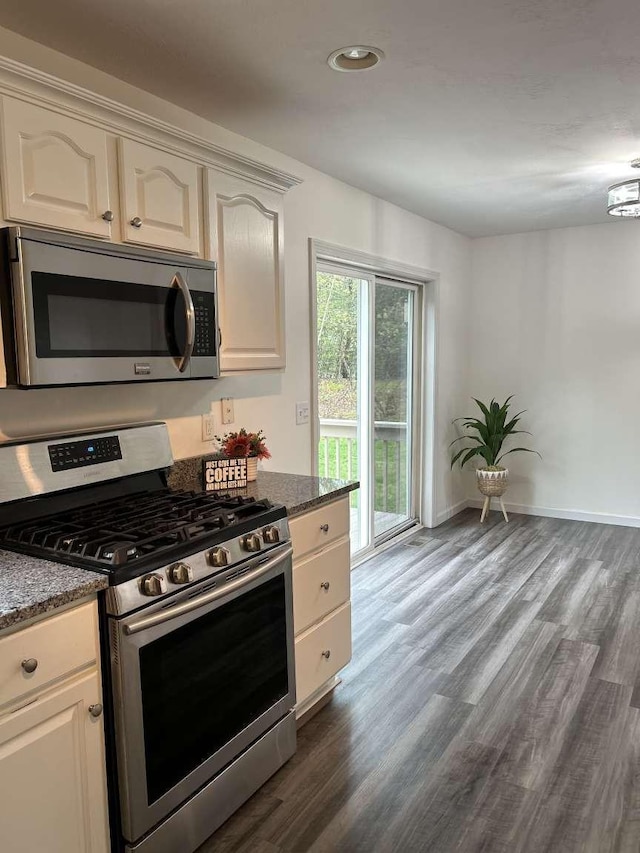 kitchen with appliances with stainless steel finishes, dark wood-style flooring, recessed lighting, stone countertops, and baseboards