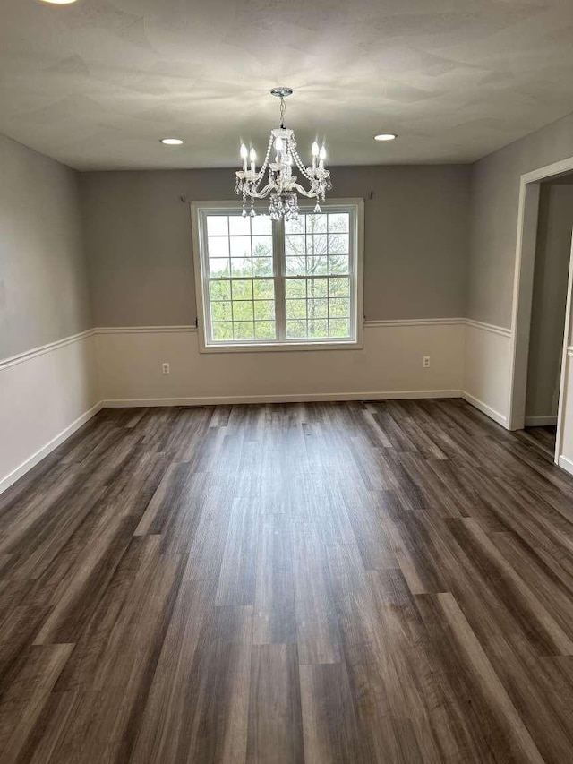 unfurnished dining area with a chandelier, dark wood-style flooring, and baseboards