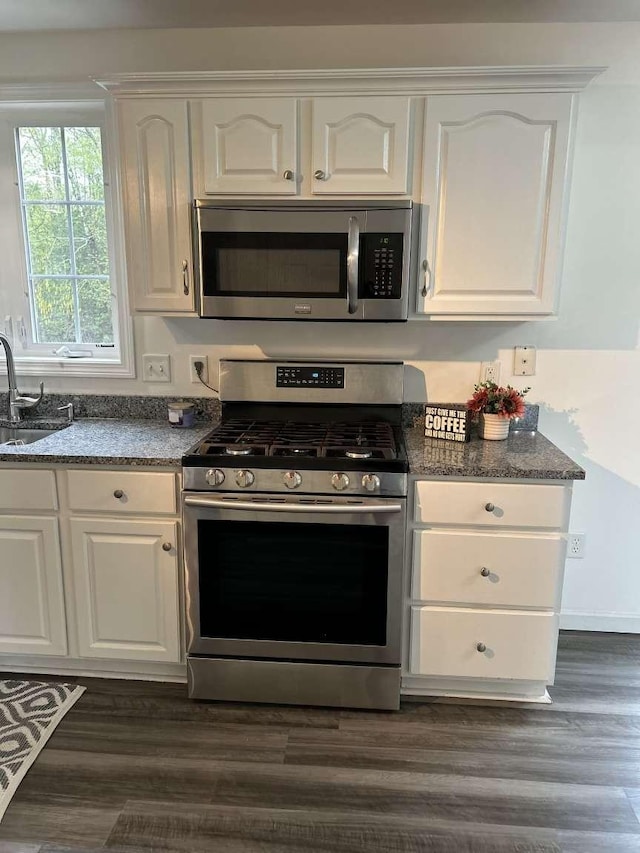 kitchen with stainless steel appliances, white cabinetry, a sink, and dark wood-style flooring