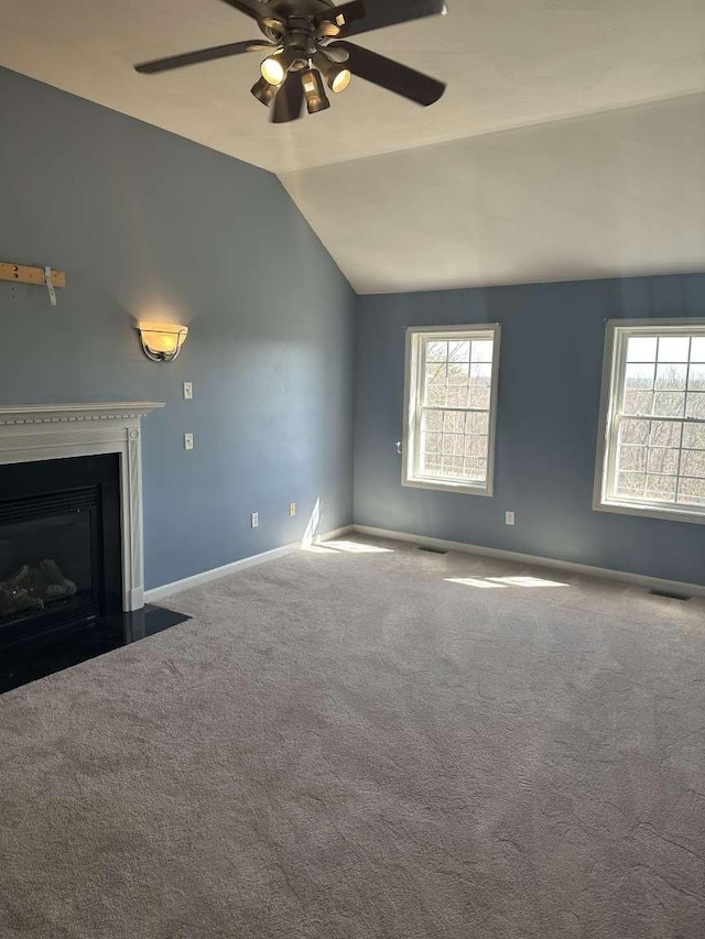 unfurnished living room featuring plenty of natural light, ceiling fan, carpet flooring, vaulted ceiling, and baseboards