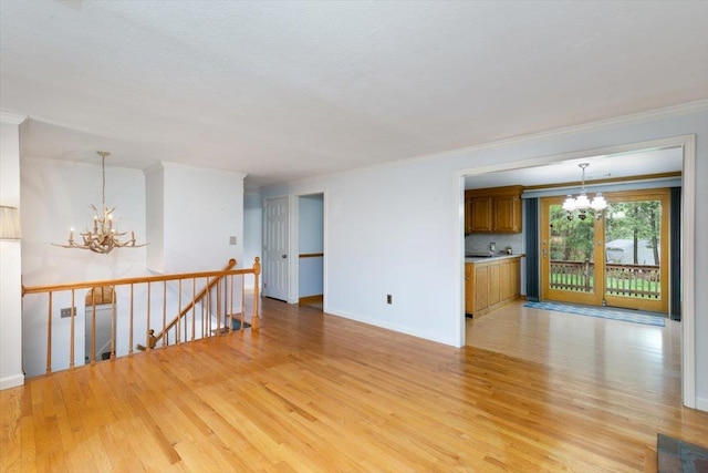 unfurnished room featuring a chandelier, light wood-style floors, ornamental molding, and baseboards