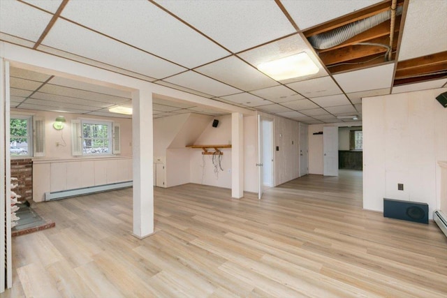 basement with baseboard heating, a paneled ceiling, and wood finished floors