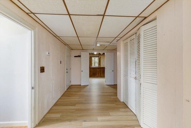 hall with a drop ceiling and light wood-style floors