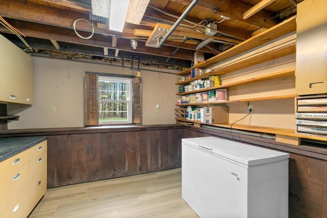 basement with white refrigerator and light wood-style flooring