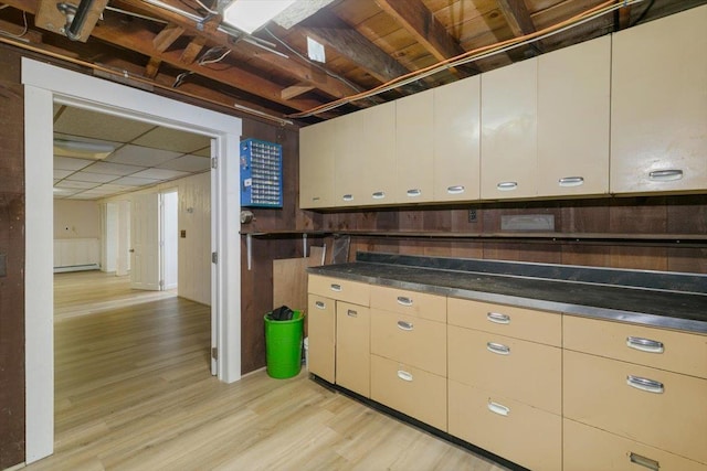 kitchen with light wood finished floors, a baseboard radiator, and dark countertops
