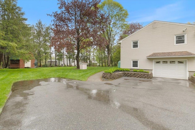 view of side of home featuring a storage unit, a garage, a yard, an outbuilding, and driveway