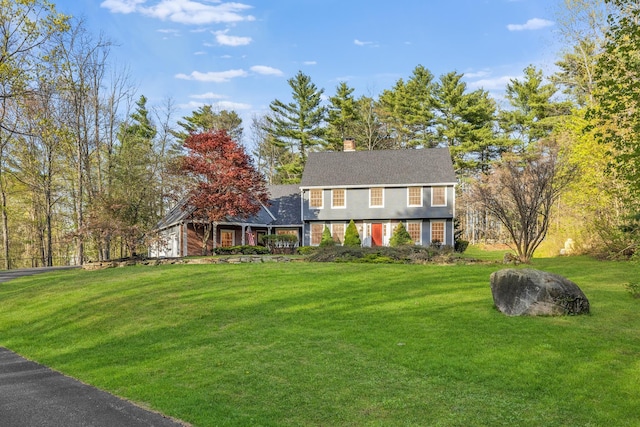 colonial inspired home with a front lawn and a chimney