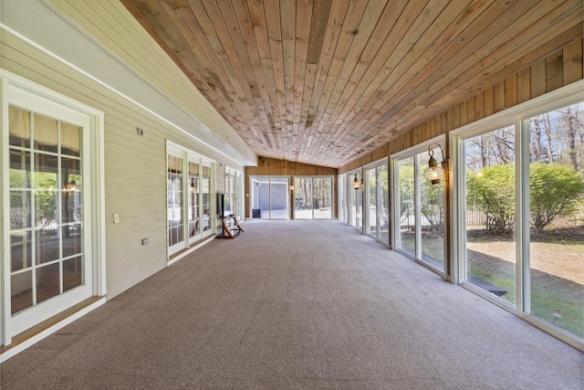 unfurnished sunroom featuring carpet flooring, healthy amount of natural light, wood walls, lofted ceiling, and wood ceiling