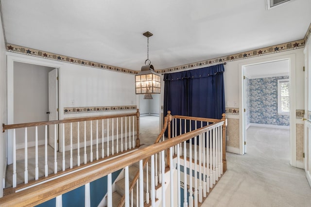 hallway with a chandelier, carpet floors, an upstairs landing, baseboards, and wallpapered walls