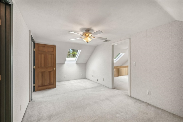 bonus room with a skylight, lofted ceiling, carpet floors, and ceiling fan