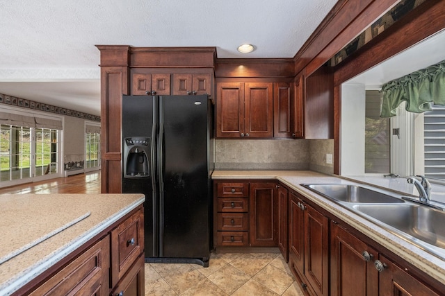 kitchen with black fridge, light countertops, a textured ceiling, decorative backsplash, and ornamental molding