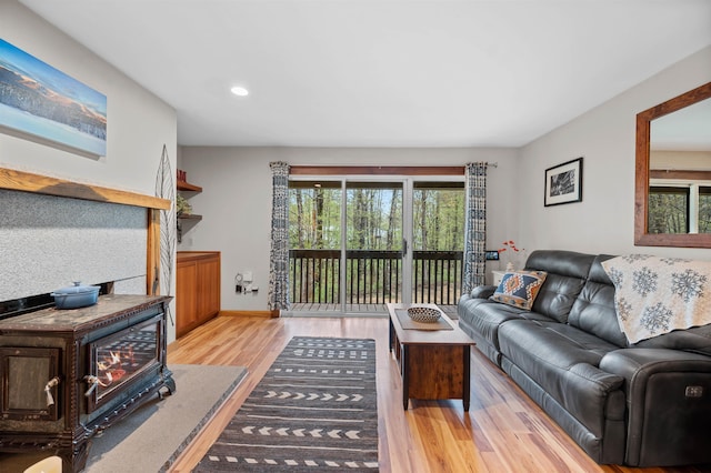 living area with wood finished floors, recessed lighting, a wood stove, and baseboards